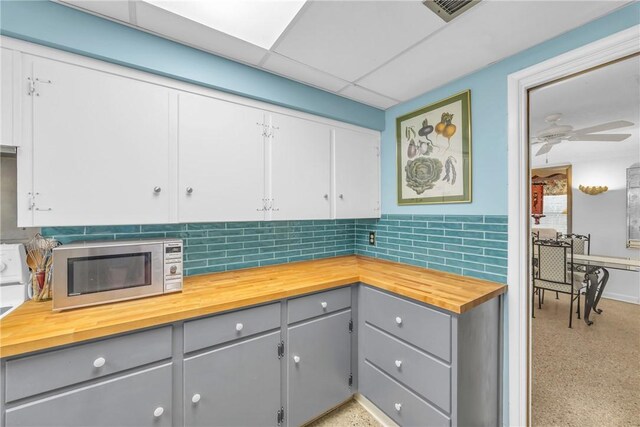 843 22nd Pl, Vero Beach, FL 32960 - kitchen with stainless steel microwave, wooden counters, gray cabinetry, and backsplash