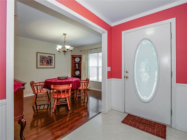 entryway featuring ornamental molding, light hardwood / wood-style flooring, a textured ceiling, and an inviting chandelier