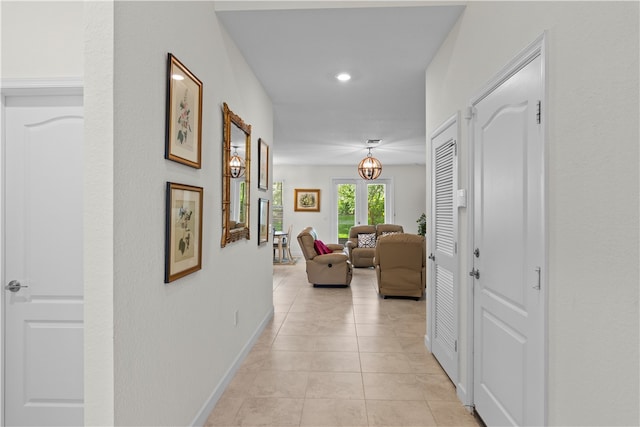 hall featuring light tile patterned floors and a notable chandelier