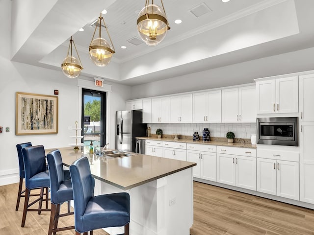 kitchen with stainless steel appliances, a center island with sink, pendant lighting, and a kitchen bar