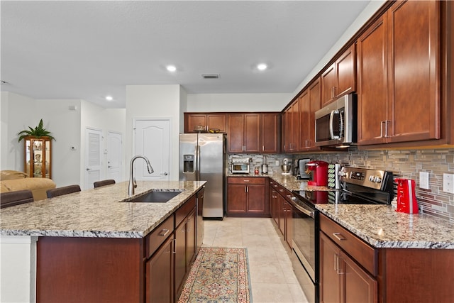 kitchen featuring light tile patterned flooring, sink, a center island with sink, stainless steel appliances, and backsplash