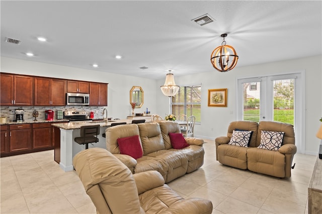 living room with an inviting chandelier, light tile patterned flooring, sink, and french doors