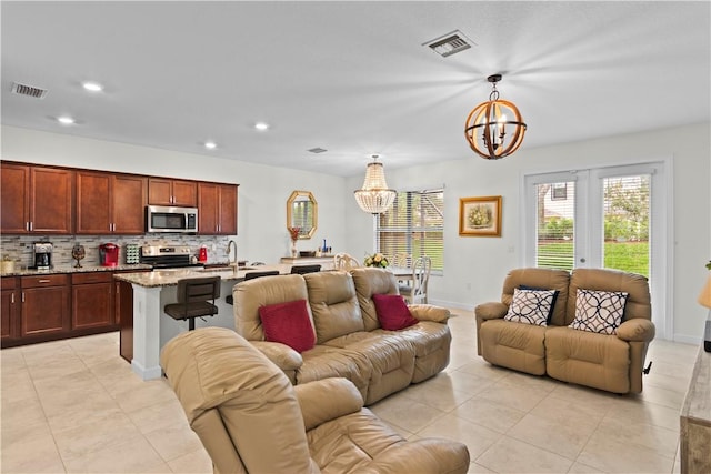 living room featuring sink, light tile patterned floors, a chandelier, and french doors