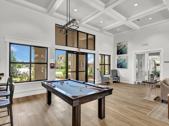 playroom with a high ceiling, beamed ceiling, light wood-type flooring, and french doors