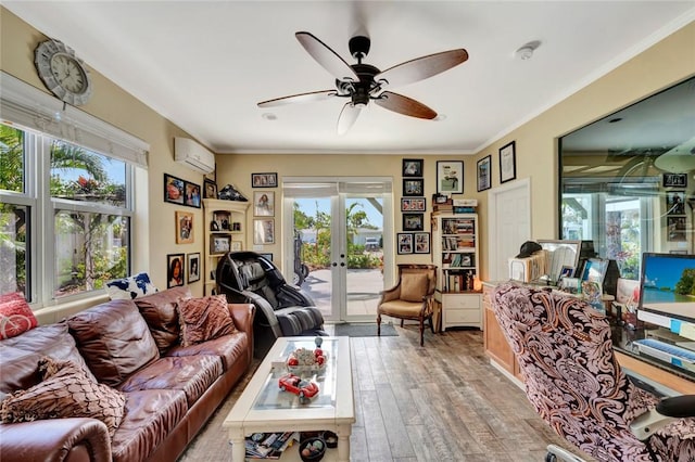 living room featuring crown molding, a wall mounted AC, light hardwood / wood-style floors, and french doors