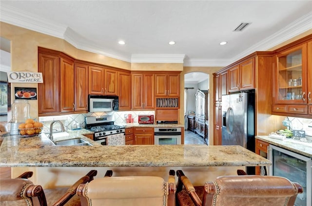 kitchen featuring appliances with stainless steel finishes, sink, a breakfast bar area, wine cooler, and kitchen peninsula