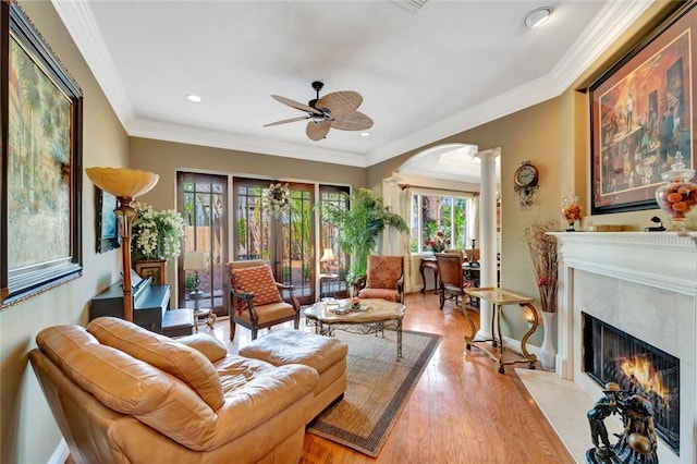 living room with ornamental molding, a fireplace, decorative columns, and light wood-type flooring