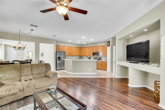 living room with ceiling fan with notable chandelier and light hardwood / wood-style flooring