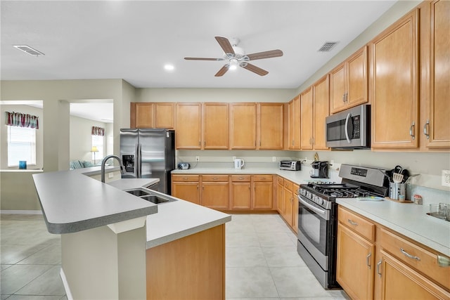 kitchen with a center island with sink, sink, ceiling fan, light tile patterned floors, and stainless steel appliances