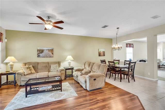 living room with hardwood / wood-style floors and ceiling fan with notable chandelier