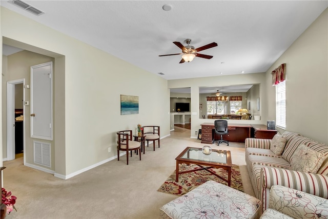 carpeted living room with ceiling fan and built in desk