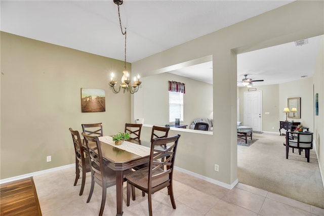 carpeted dining space with ceiling fan with notable chandelier