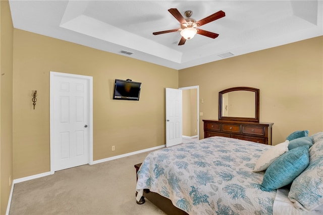 carpeted bedroom with a tray ceiling and ceiling fan