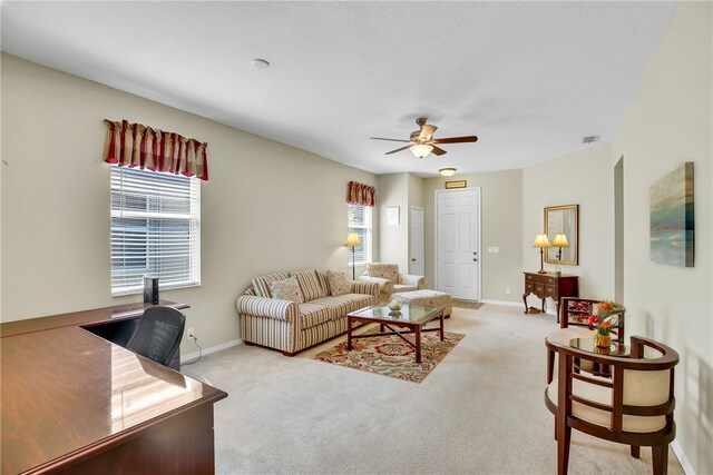 living room featuring light carpet, ceiling fan, and a healthy amount of sunlight