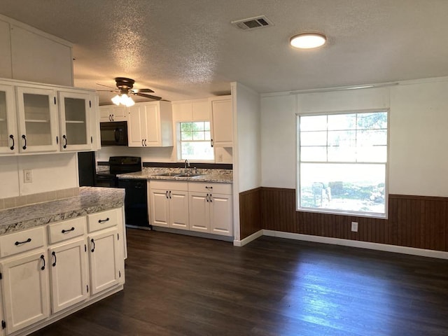 10186 NE 30th St, Okeechobee, FL 34974 - kitchen with black appliances, a wainscoted wall, white cabinetry, dark wood-type flooring, and a textured ceiling