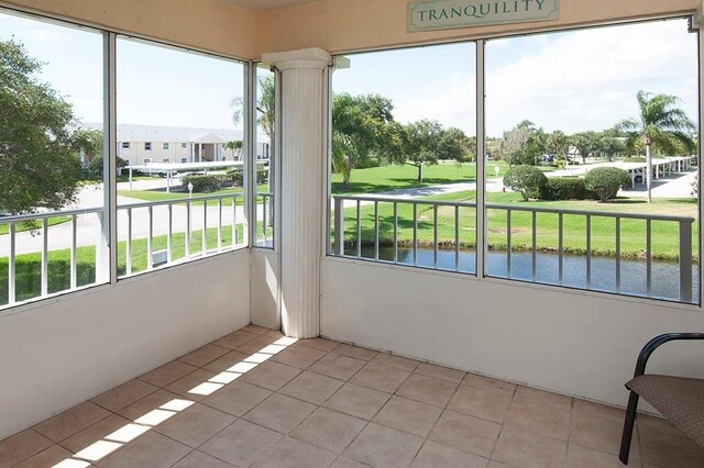 unfurnished sunroom with decorative columns, tile patterned floors, and a water view