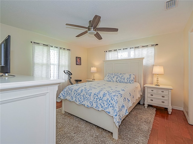 bedroom featuring hardwood / wood-style floors, multiple windows, and ceiling fan