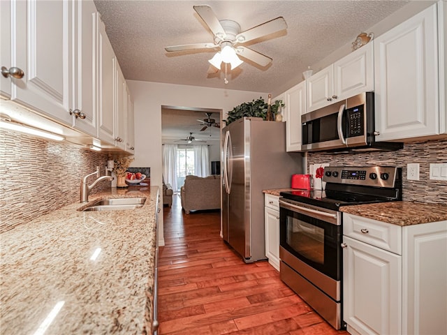 kitchen featuring sink, light hardwood / wood-style floors, light stone counters, white cabinetry, and stainless steel appliances