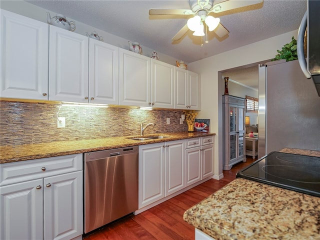 kitchen with light stone countertops, stainless steel appliances, dark wood-type flooring, sink, and white cabinets