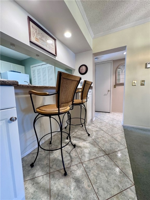 unfurnished dining area featuring a textured ceiling, light tile patterned flooring, and crown molding