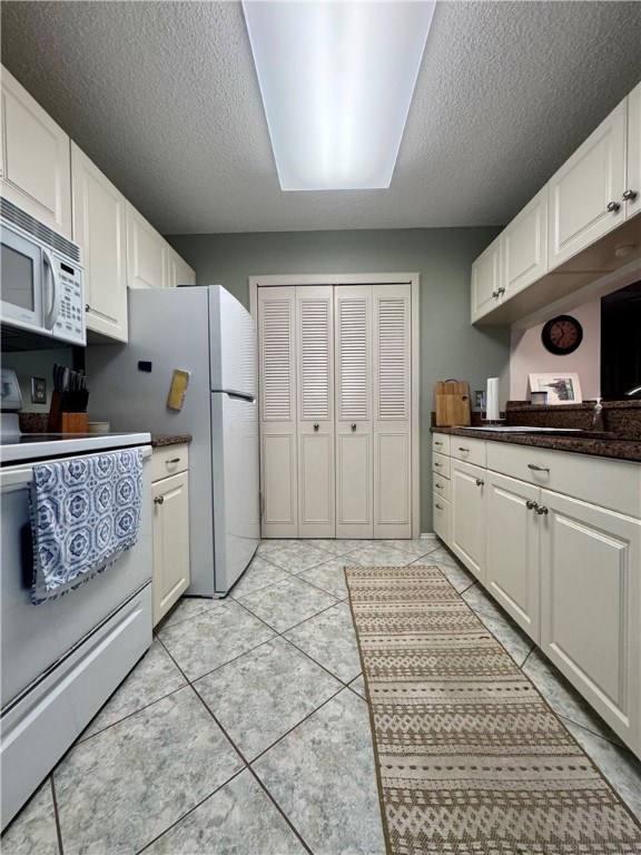 kitchen with white appliances, a textured ceiling, and white cabinets