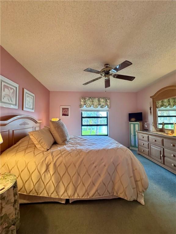 carpeted bedroom with ceiling fan and a textured ceiling