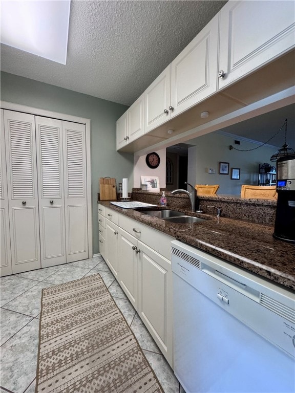 kitchen with sink, dishwasher, dark stone countertops, and white cabinetry