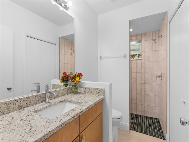 bathroom with toilet, tile patterned floors, tiled shower, and vanity