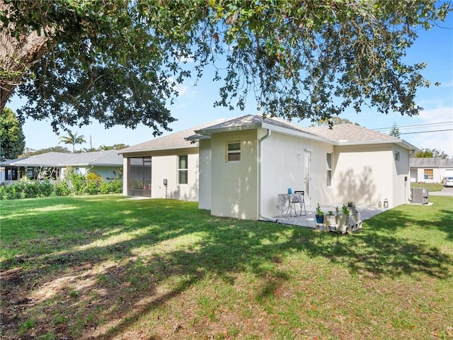 rear view of property with a yard, central air condition unit, and a sunroom