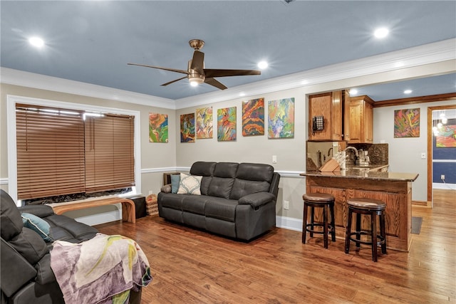 living room featuring light hardwood / wood-style floors, ceiling fan, and ornamental molding