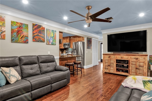 living room featuring ornamental molding, wood-type flooring, and ceiling fan