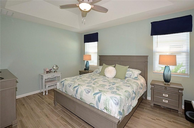 bedroom with multiple windows, a raised ceiling, and wood tiled floor