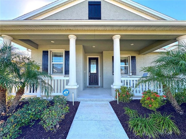 property entrance with covered porch and stucco siding