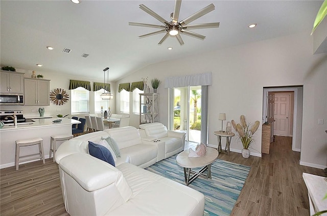 living room with dark wood-style floors, lofted ceiling, visible vents, and recessed lighting