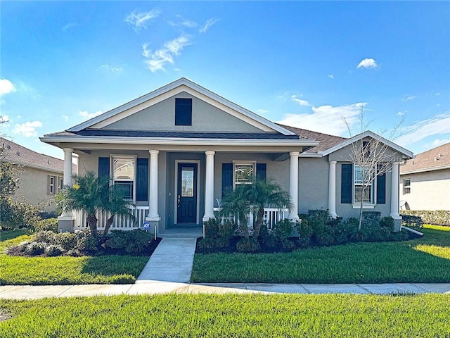 view of front facade with covered porch, a front yard, and stucco siding