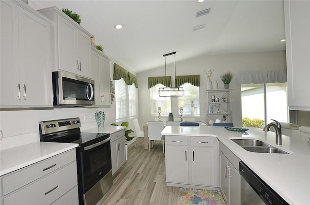 kitchen featuring visible vents, lofted ceiling, appliances with stainless steel finishes, light countertops, and a sink