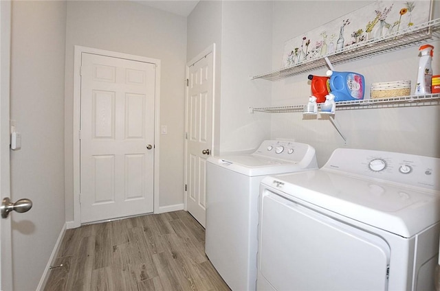 clothes washing area featuring light wood-style floors, laundry area, washer and clothes dryer, and baseboards