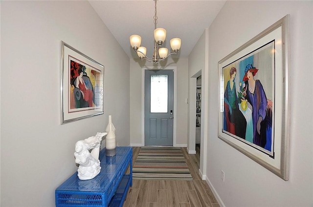 entryway featuring baseboards, a chandelier, and wood finished floors