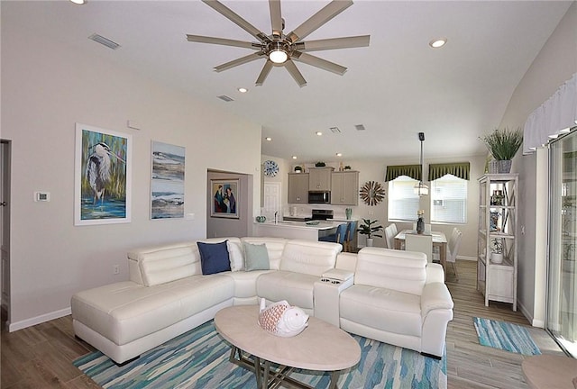 living area with visible vents, baseboards, wood finished floors, and recessed lighting