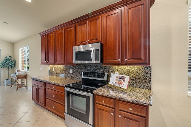 kitchen with appliances with stainless steel finishes, stone counters, backsplash, and light tile patterned floors