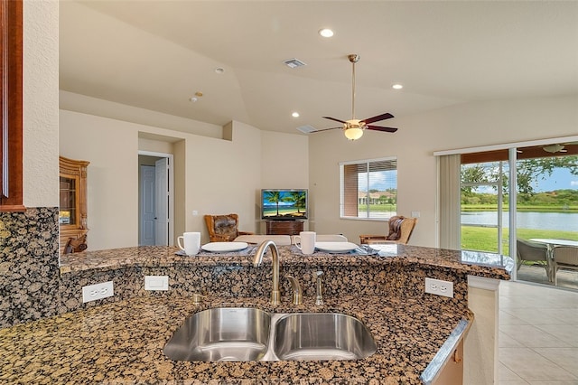 kitchen featuring sink, dark stone counters, ceiling fan, light tile patterned floors, and lofted ceiling