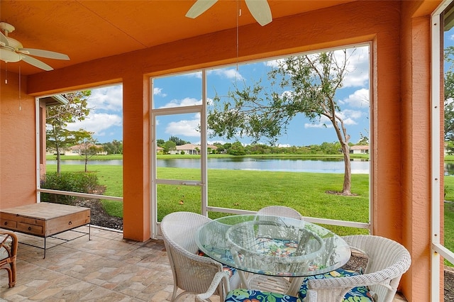 sunroom with a water view, a healthy amount of sunlight, and ceiling fan