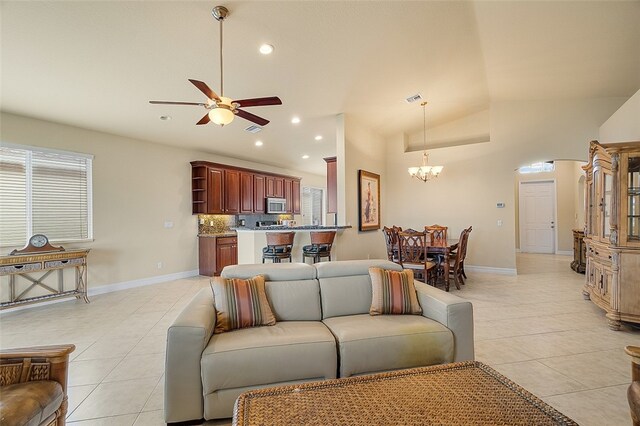 tiled living room featuring ceiling fan with notable chandelier and vaulted ceiling