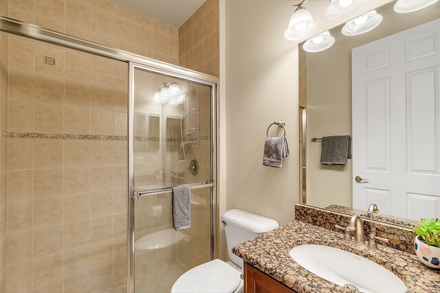 bathroom featuring vanity, toilet, and a shower with door