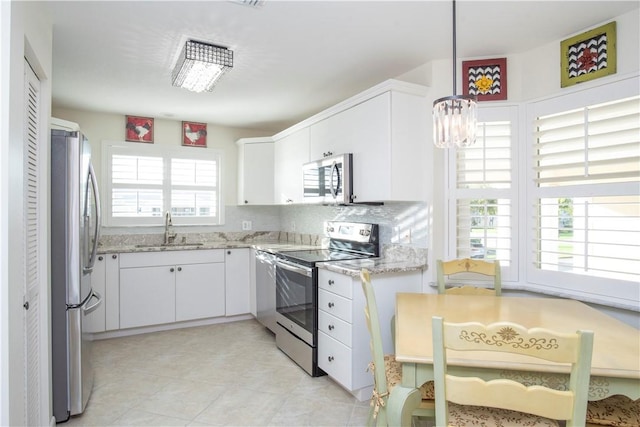 kitchen with decorative backsplash, white cabinets, appliances with stainless steel finishes, light stone countertops, and a sink