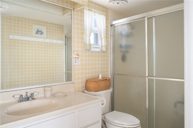 bathroom with vanity, toilet, and a shower with shower door