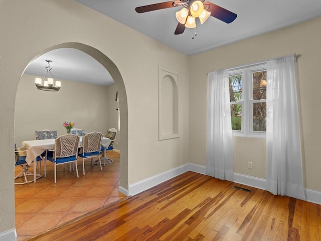2237 10th Ave, Vero Beach, FL 32960 - empty room featuring wood finished floors, visible vents, arched walkways, baseboards, and ceiling fan with notable chandelier