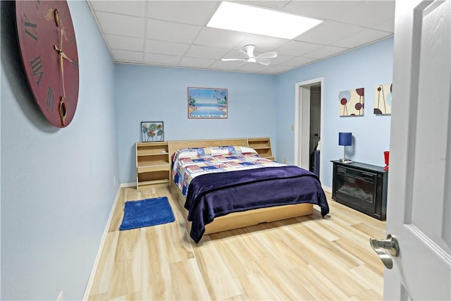 bedroom with ceiling fan, a paneled ceiling, and wood-type flooring