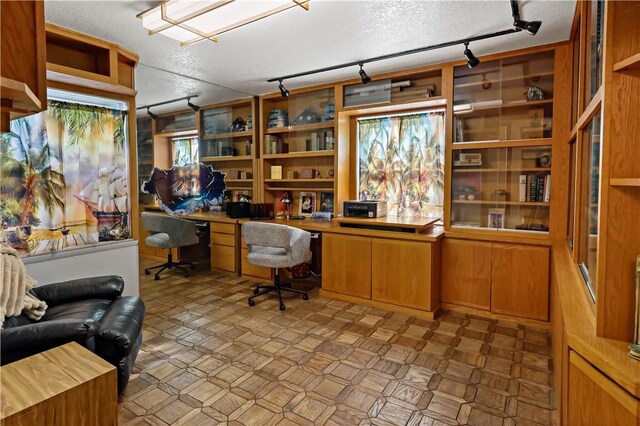 office space with built in desk and a textured ceiling