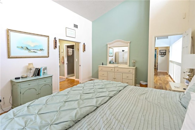 bedroom featuring light wood-type flooring and high vaulted ceiling